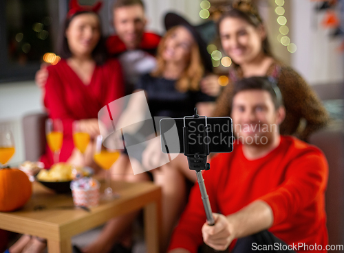 Image of happy friends in halloween costumes taking selfie