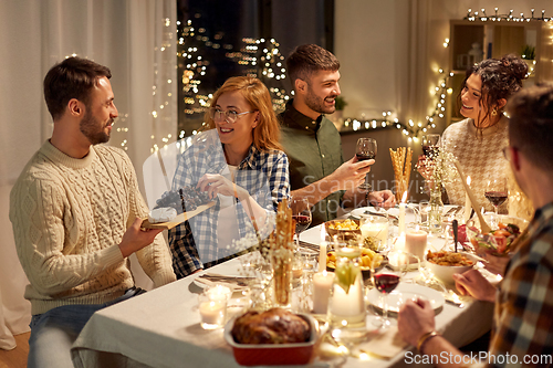 Image of happy friends having christmas dinner at home