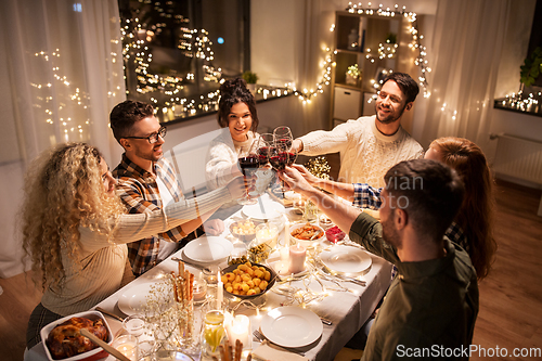 Image of happy friends drinking red wine at christmas party