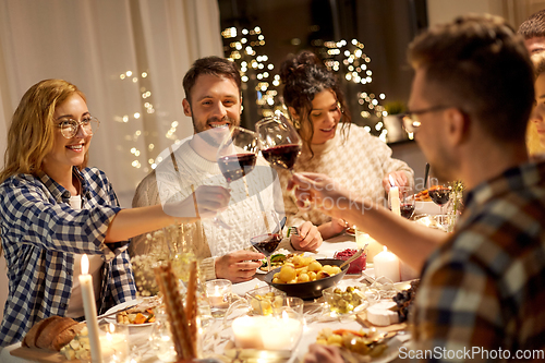 Image of happy friends drinking red wine at christmas party