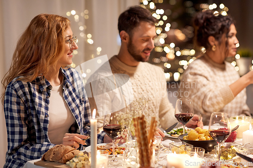 Image of happy friends having christmas dinner at home