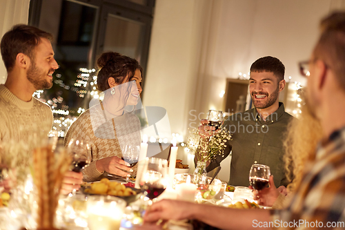 Image of happy friends drinking red wine at christmas party