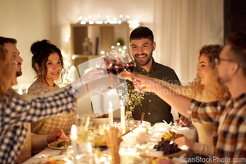 Image of happy friends drinking red wine at christmas party