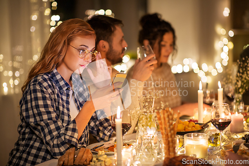 Image of woman with smartphone at dinner party with friends