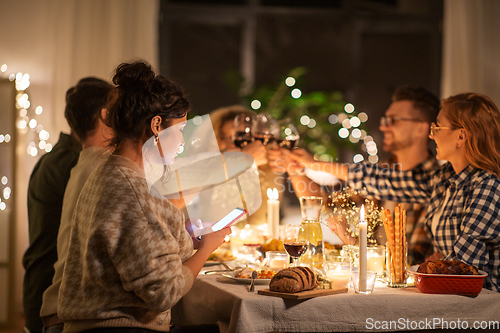 Image of woman with smartphone at dinner party with friends