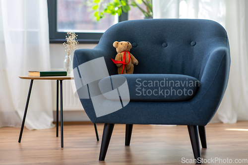 Image of modern armchair with teddy bear toy at home