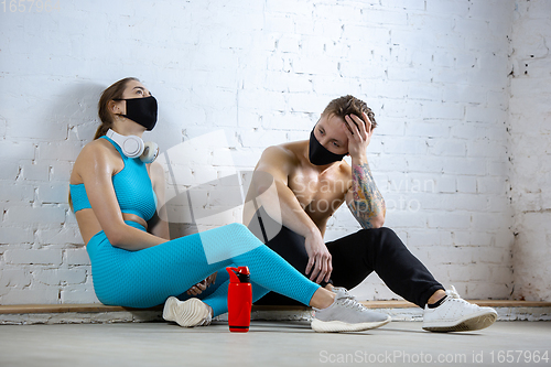 Image of Professional athletes training on brick wall background wearing face mask. Sport during quarantine