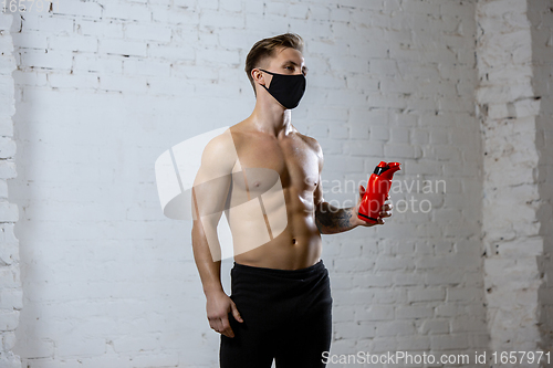 Image of Professional male athlete training on brick wall background wearing face mask. Sport during quarantine