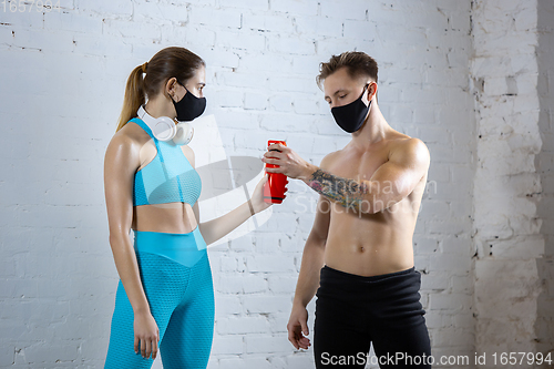 Image of Professional athletes training on brick wall background wearing face mask. Sport during quarantine
