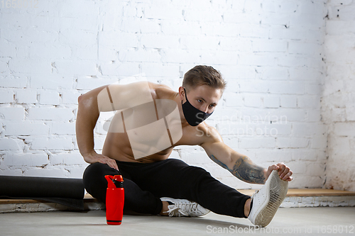 Image of Professional male athlete training on brick wall background wearing face mask. Sport during quarantine