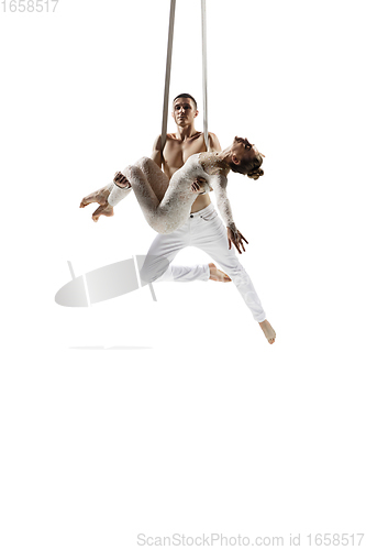 Image of Couple of young acrobats, circus athletes isolated on white studio background. Training perfect balanced in flight