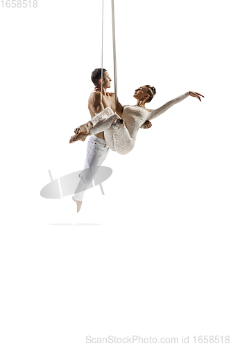 Image of Couple of young acrobats, circus athletes isolated on white studio background. Training perfect balanced in flight