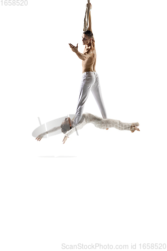 Image of Couple of young acrobats, circus athletes isolated on white studio background. Training perfect balanced in flight