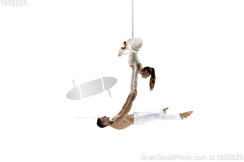 Image of Couple of young acrobats, circus athletes isolated on white studio background. Training perfect balanced in flight