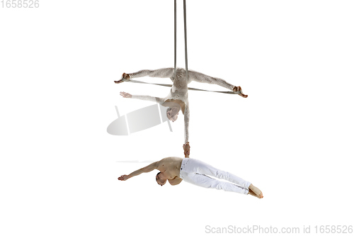 Image of Couple of young acrobats, circus athletes isolated on white studio background. Training perfect balanced in flight