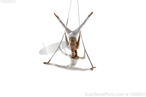 Image of Couple of young acrobats, circus athletes isolated on white studio background. Training perfect balanced in flight