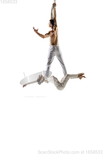 Image of Couple of young acrobats, circus athletes isolated on white studio background. Training perfect balanced in flight