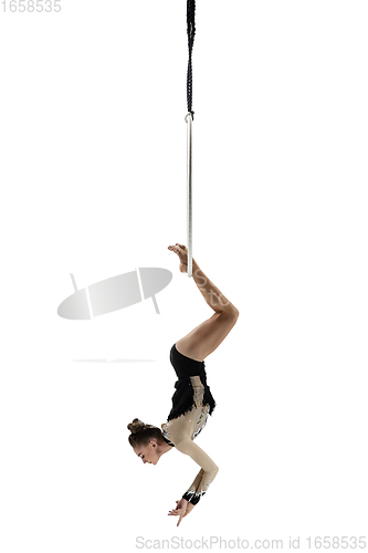 Image of Young female acrobat, circus athlete isolated on white studio background. Training perfect balanced in flight