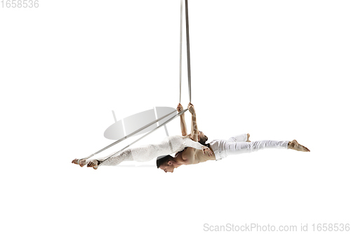 Image of Couple of young acrobats, circus athletes isolated on white studio background. Training perfect balanced in flight