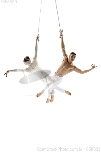 Image of Couple of young acrobats, circus athletes isolated on white studio background. Training perfect balanced in flight