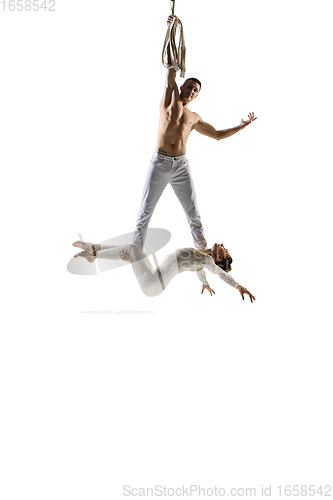 Image of Couple of young acrobats, circus athletes isolated on white studio background. Training perfect balanced in flight