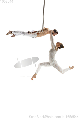 Image of Couple of young acrobats, circus athletes isolated on white studio background. Training perfect balanced in flight