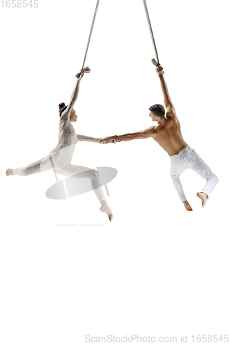 Image of Couple of young acrobats, circus athletes isolated on white studio background. Training perfect balanced in flight