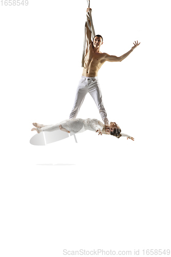 Image of Couple of young acrobats, circus athletes isolated on white studio background. Training perfect balanced in flight