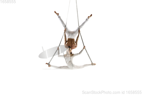 Image of Couple of young acrobats, circus athletes isolated on white studio background. Training perfect balanced in flight