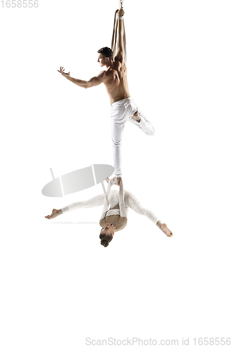 Image of Couple of young acrobats, circus athletes isolated on white studio background. Training perfect balanced in flight