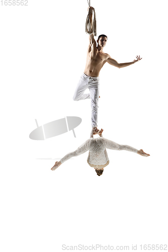 Image of Couple of young acrobats, circus athletes isolated on white studio background. Training perfect balanced in flight