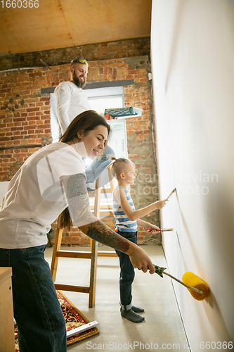 Image of Young family doing apartment repair together themselves. Mother, father and son doing home makeover or renovation