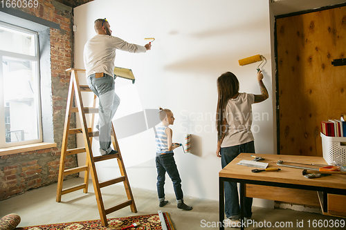 Image of Young family doing apartment repair together themselves. Mother, father and son doing home makeover or renovation