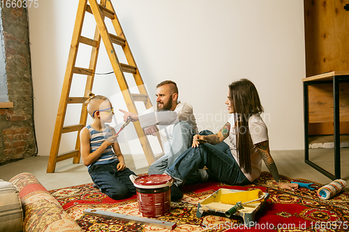 Image of Young family doing apartment repair together themselves. Mother, father and son doing home makeover or renovation