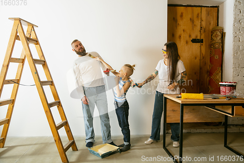 Image of Young family doing apartment repair together themselves. Mother, father and son doing home makeover or renovation