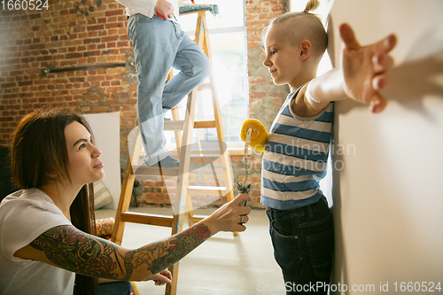 Image of Young family doing apartment repair together themselves. Mother, father and son doing home makeover or renovation