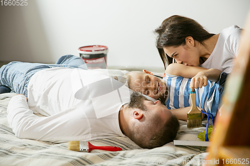 Image of Young family doing apartment repair together themselves. Mother, father and son doing home makeover or renovation