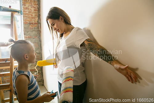 Image of Young family doing apartment repair together themselves. Happy mother and son doing home makeover or renovation