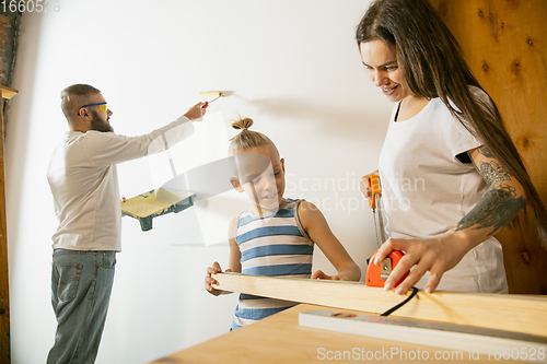 Image of Young family doing apartment repair together themselves. Mother, father and son doing home makeover or renovation