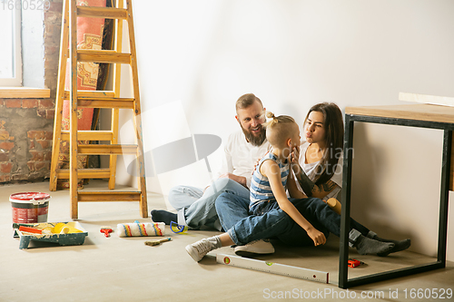 Image of Young family doing apartment repair together themselves. Mother, father and son doing home makeover or renovation