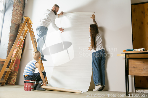 Image of Young family doing apartment repair together themselves. Mother, father and son doing home makeover or renovation