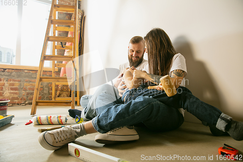 Image of Young family doing apartment repair together themselves. Mother, father and son doing home makeover or renovation