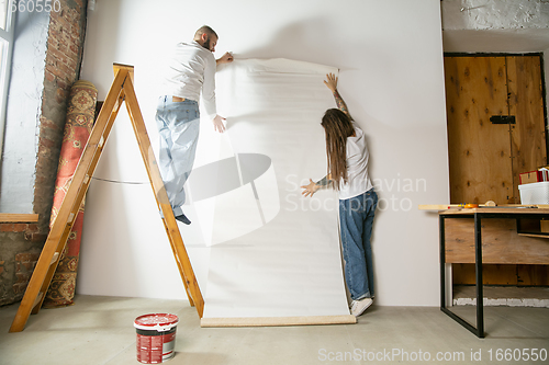 Image of Young family doing apartment repair together themselves. Married man and woman doing home makeover or renovation