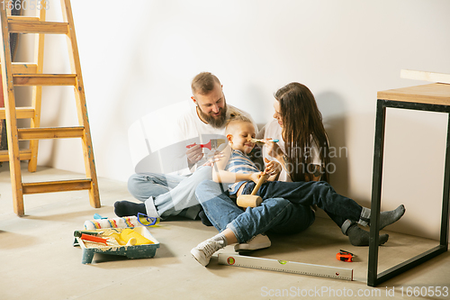 Image of Young family doing apartment repair together themselves. Mother, father and son doing home makeover or renovation