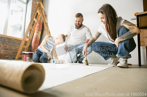 Image of Young family doing apartment repair together themselves. Mother, father and son doing home makeover or renovation