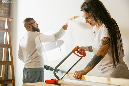 Image of Young family doing apartment repair together themselves. Married man and woman doing home makeover or renovation