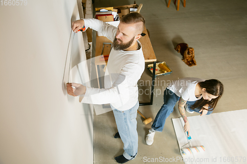 Image of Young family doing apartment repair together themselves. Married man and woman doing home makeover or renovation