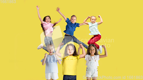 Image of Portrait of little children jumping isolated on yellow studio background with copyspace