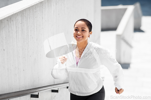 Image of african american woman running upstairs outdoors