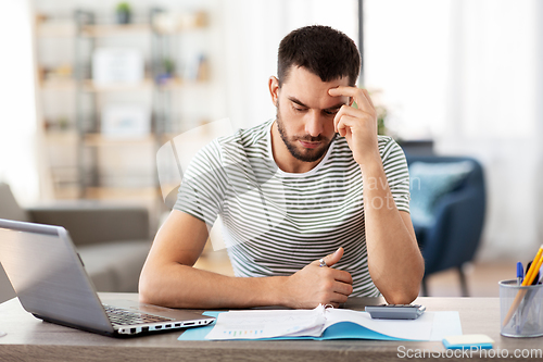 Image of man with files and calculator works at home office